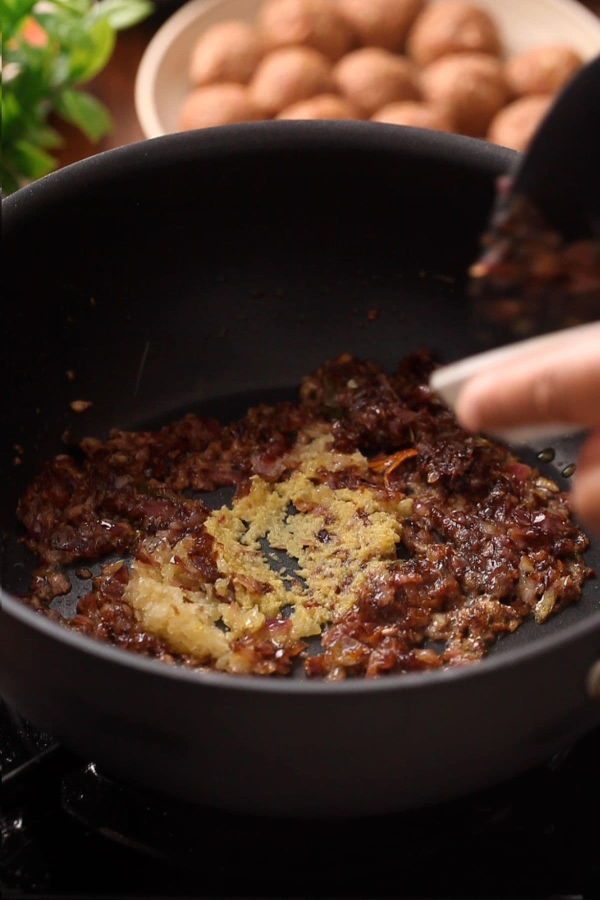 Browned onions, ginger and garlic in a black cooking pot.