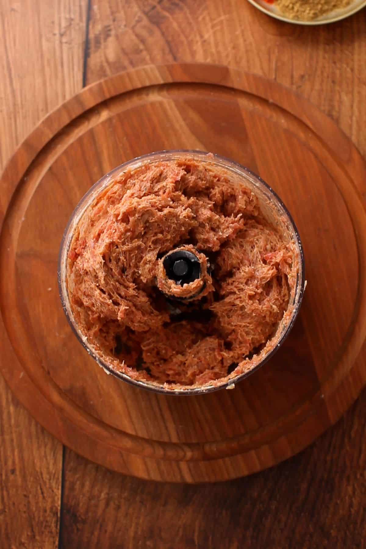 A top-down view of a food processor containing a blended kofta mixture.
