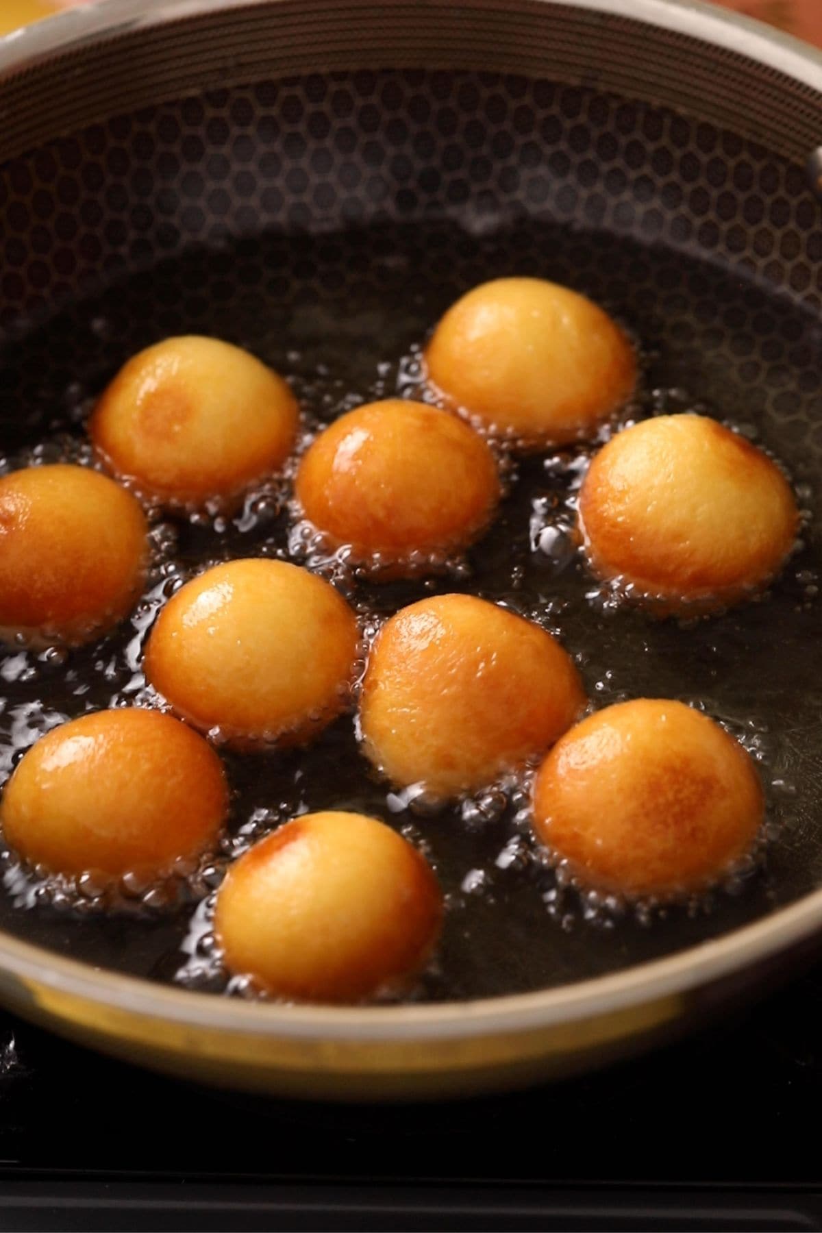 Gulab jamun are frying in oil.