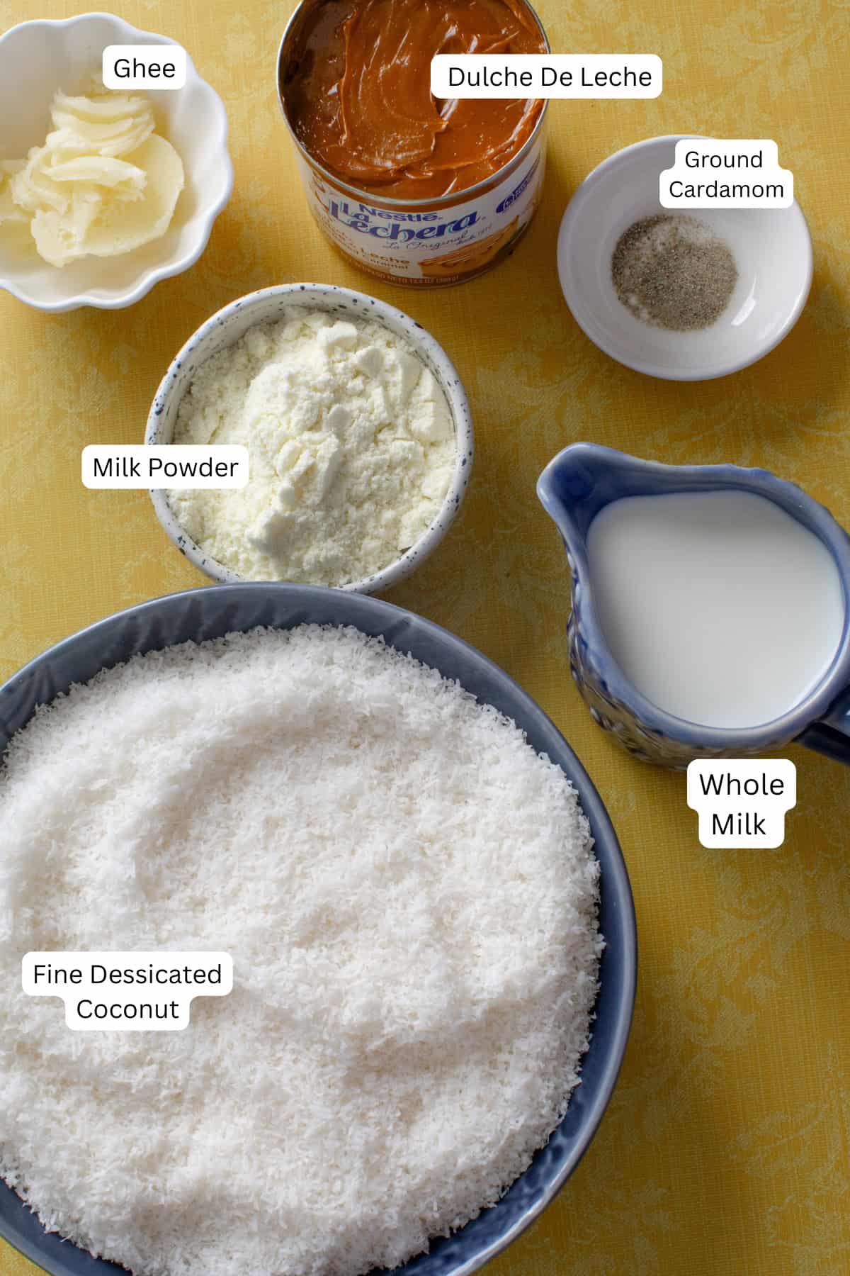 Ingredients for coconut burfi are placed on a yellow background.