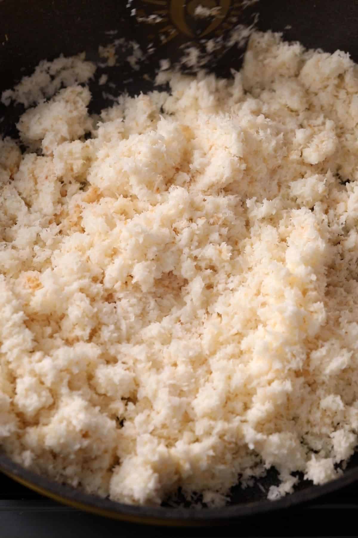 Milk hydrated dessicated coconut is stirred using a spatula.