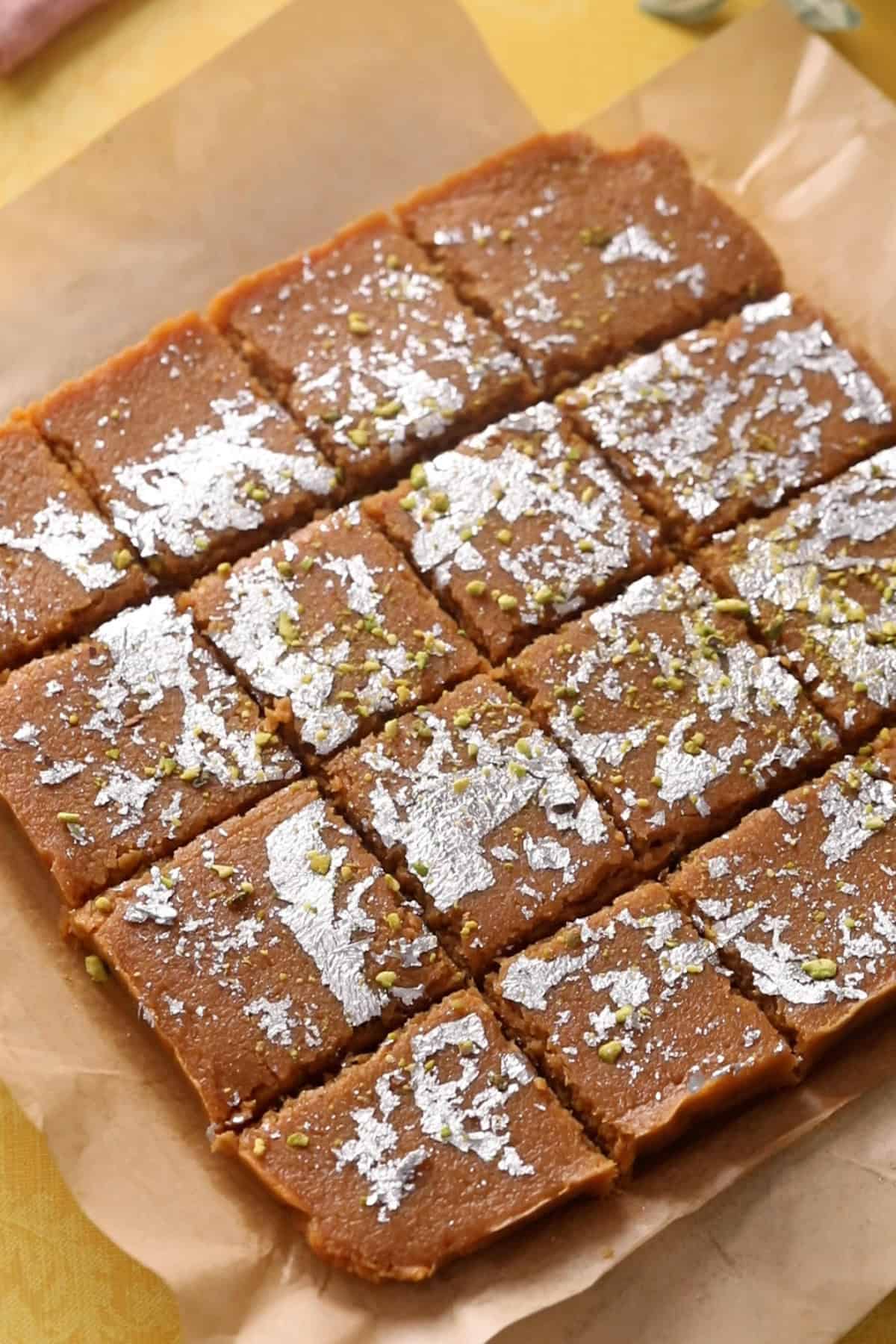 Coconut burfi is cut into neat squares using a sharp knife.