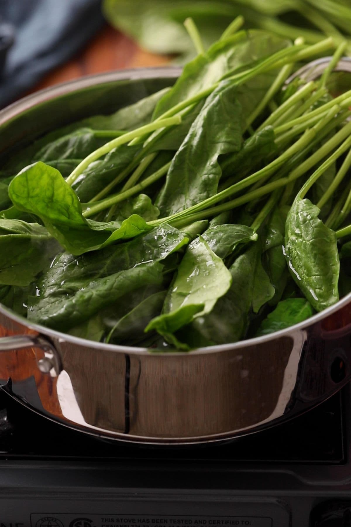Fresh spinach are added to large pot of boiling water.