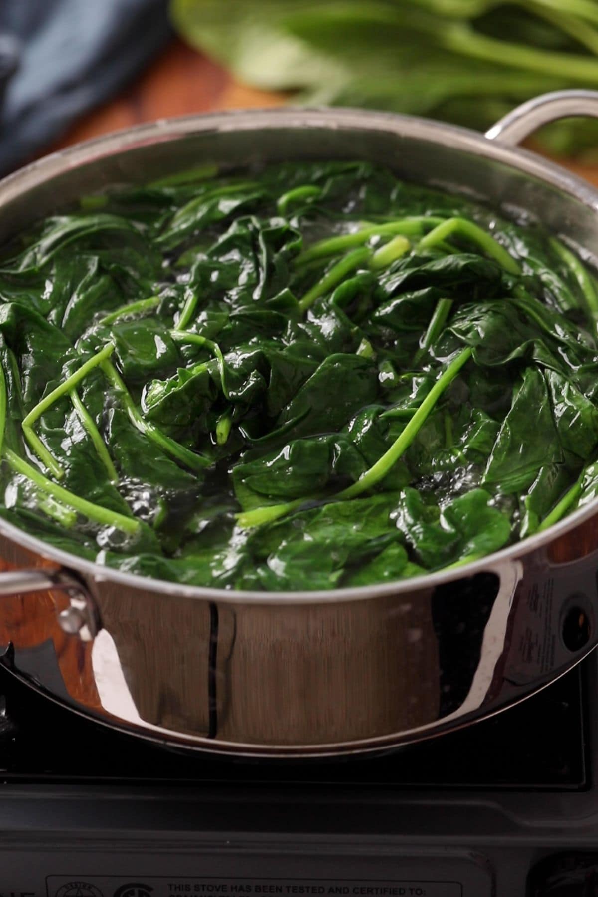 Spinach leaves are wilted in boiling water.