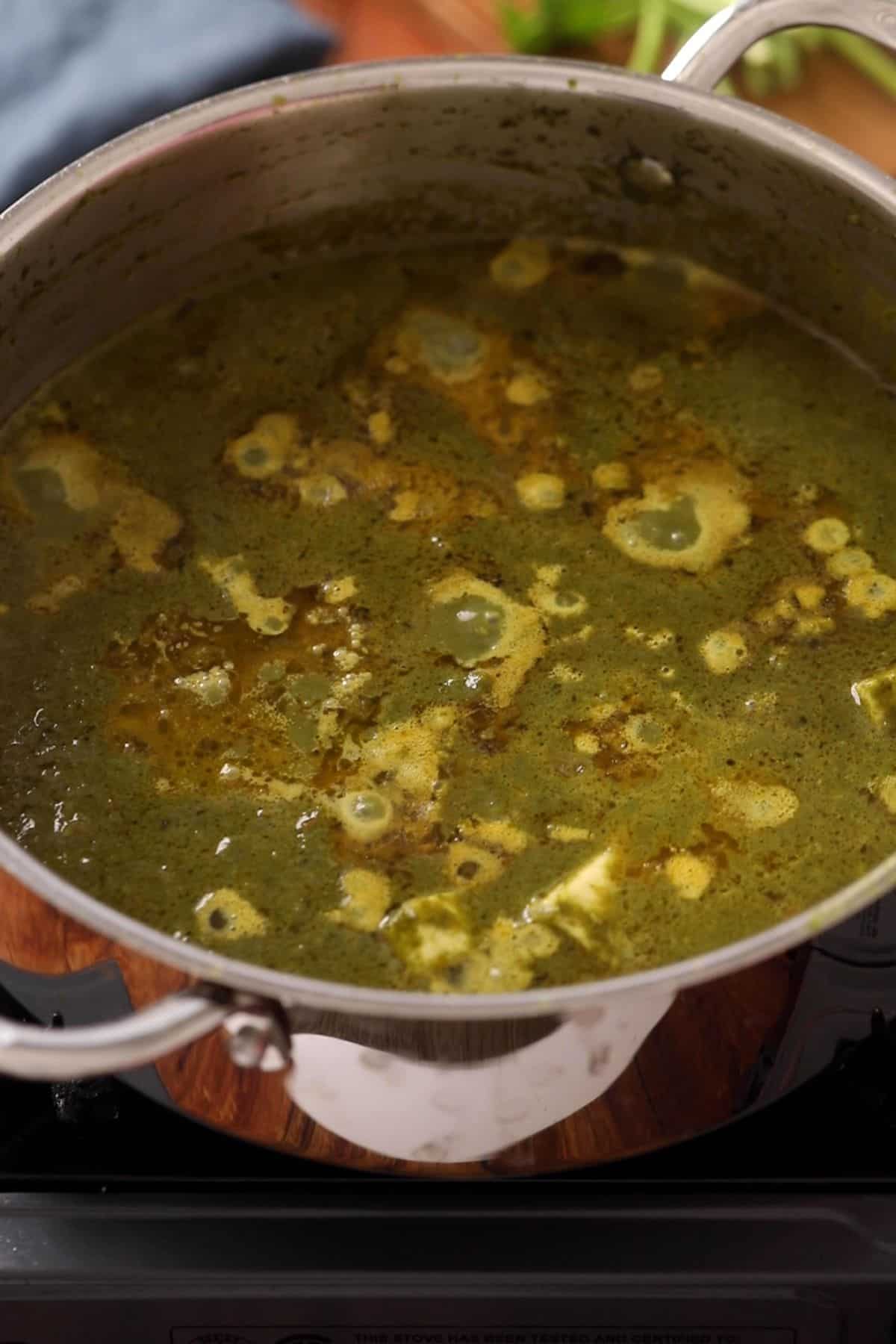 Spinach paneer is simmered until oil floats on top.