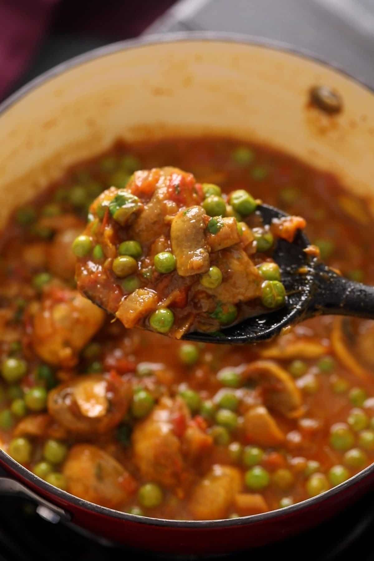 Mushroom matar sabzi is being shown in a black spoon.