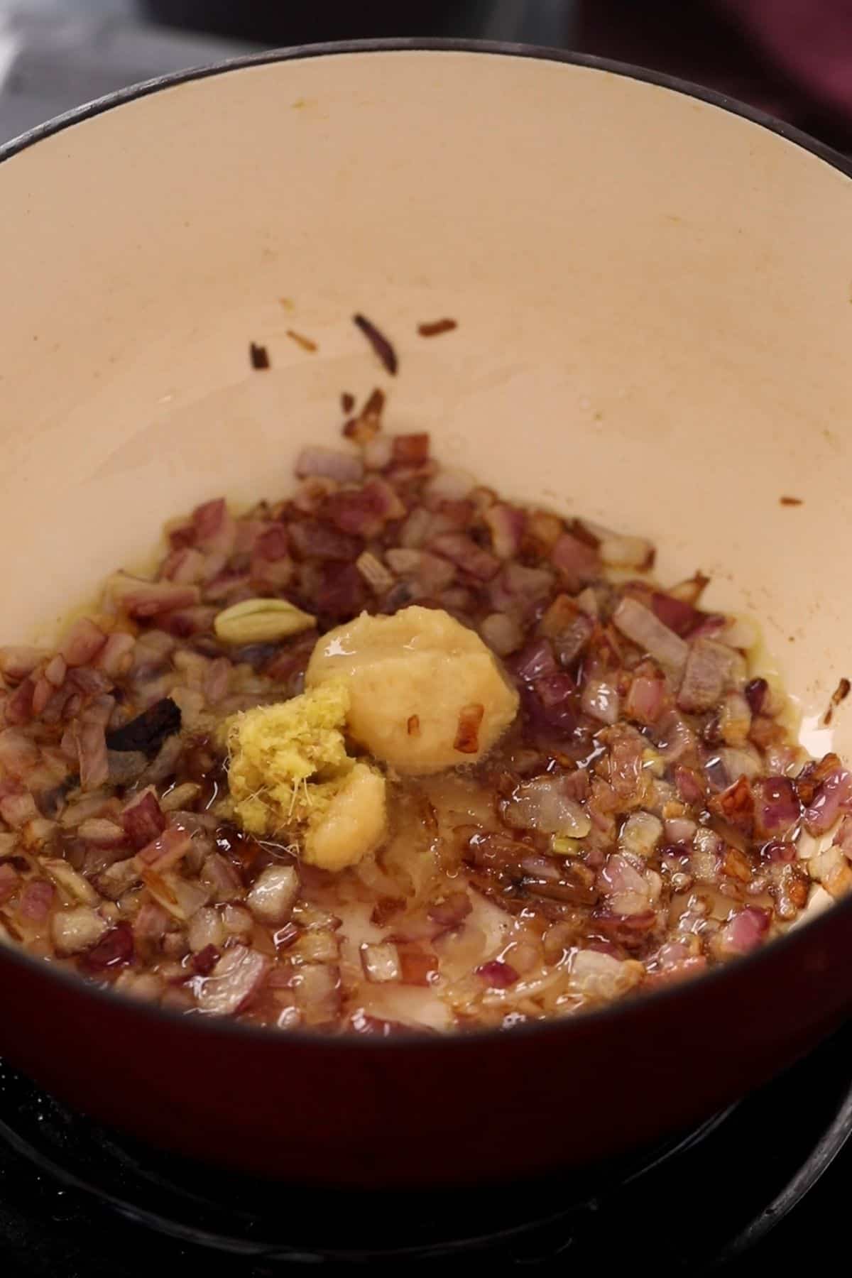 Ginger and garlic paste are added to browned onions.
