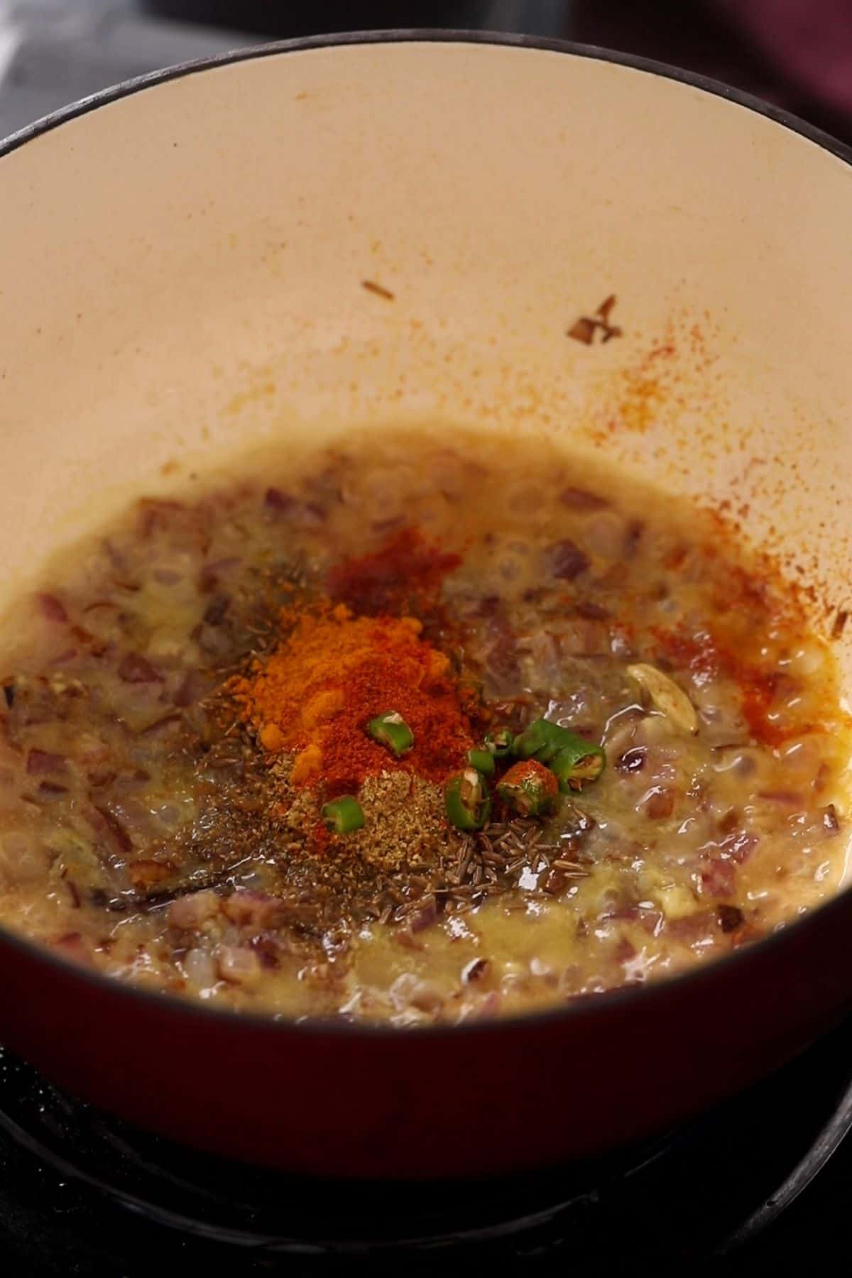 Ground spices and chopped green chilies are added to the onion.