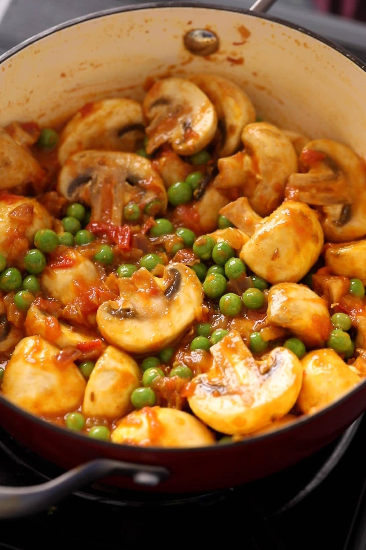 White mushrooms and green peas are added to the masala.