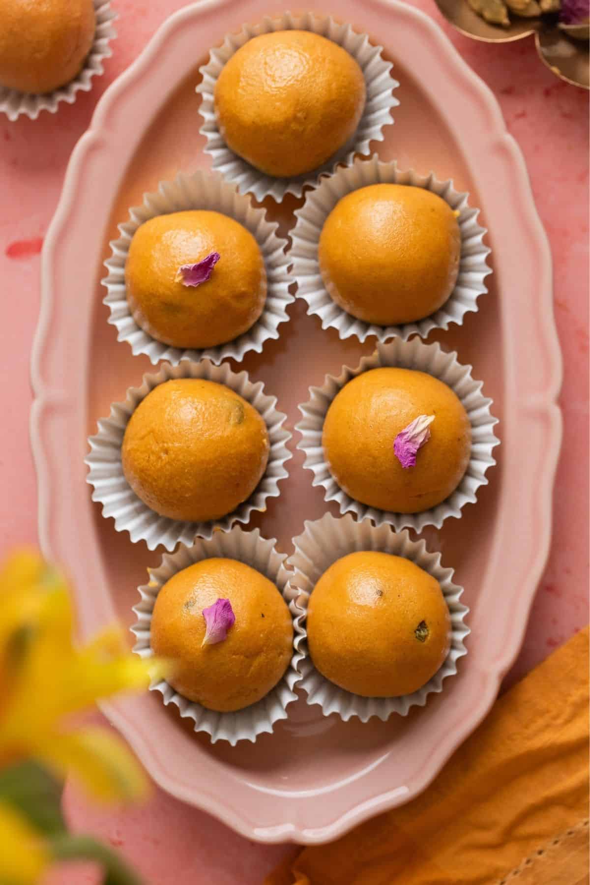 Homemade besan ladoo on an oval pink platter. 