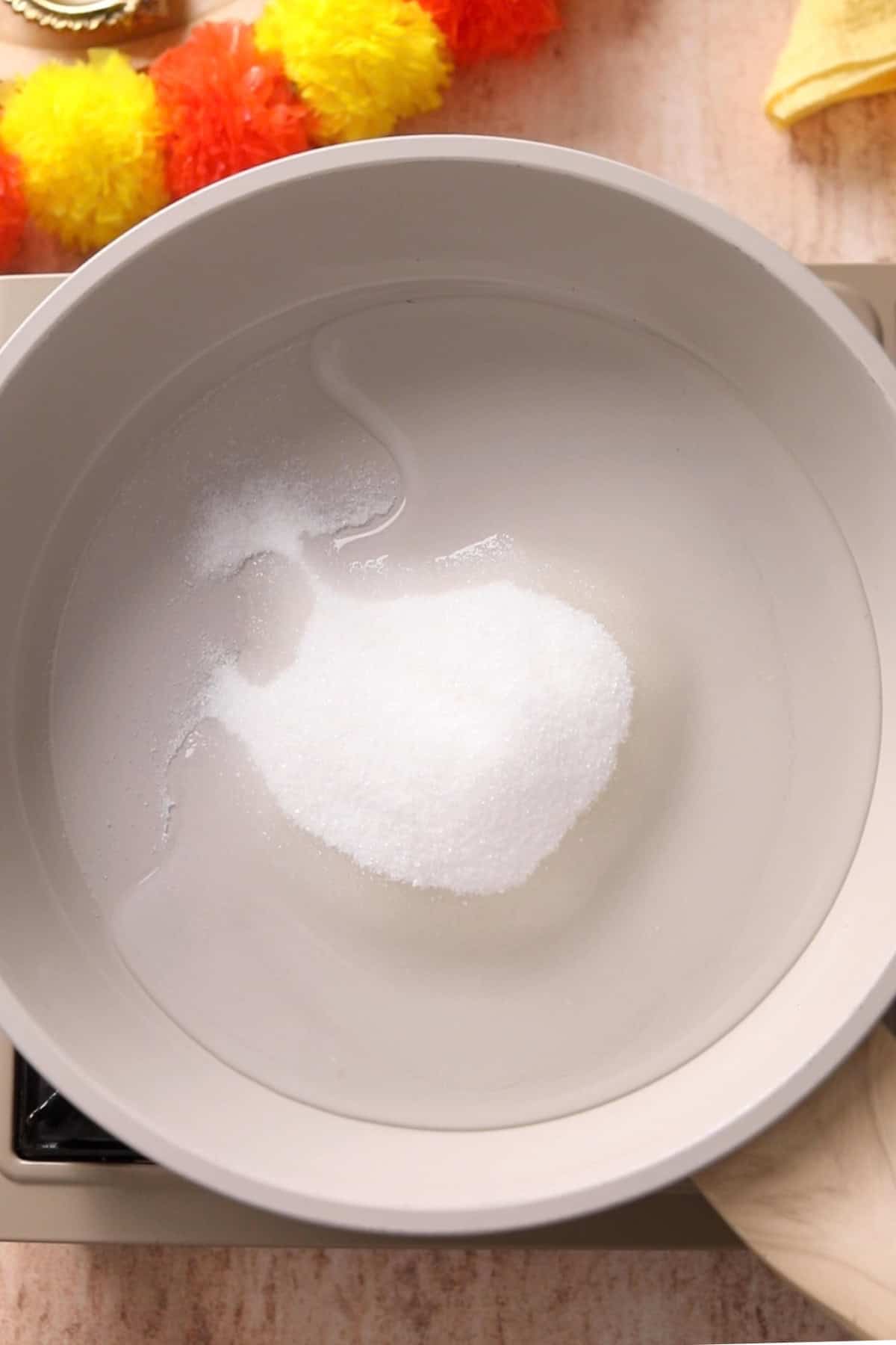Sugar and water in a beige colored non stick pan.