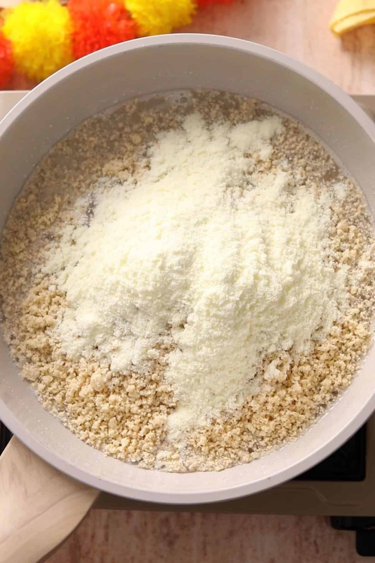 Ground cashew powder and milk powder are added to the sugar syrup.