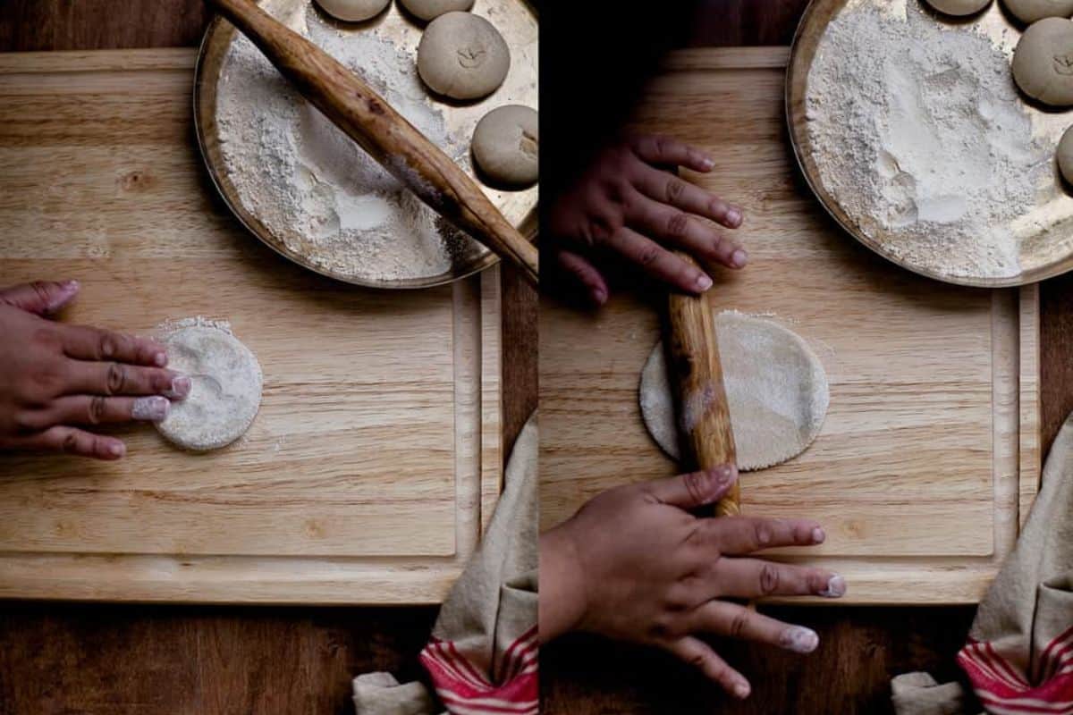 The dough balls are flattened on a wooden surface and rolled with a rolling pin.