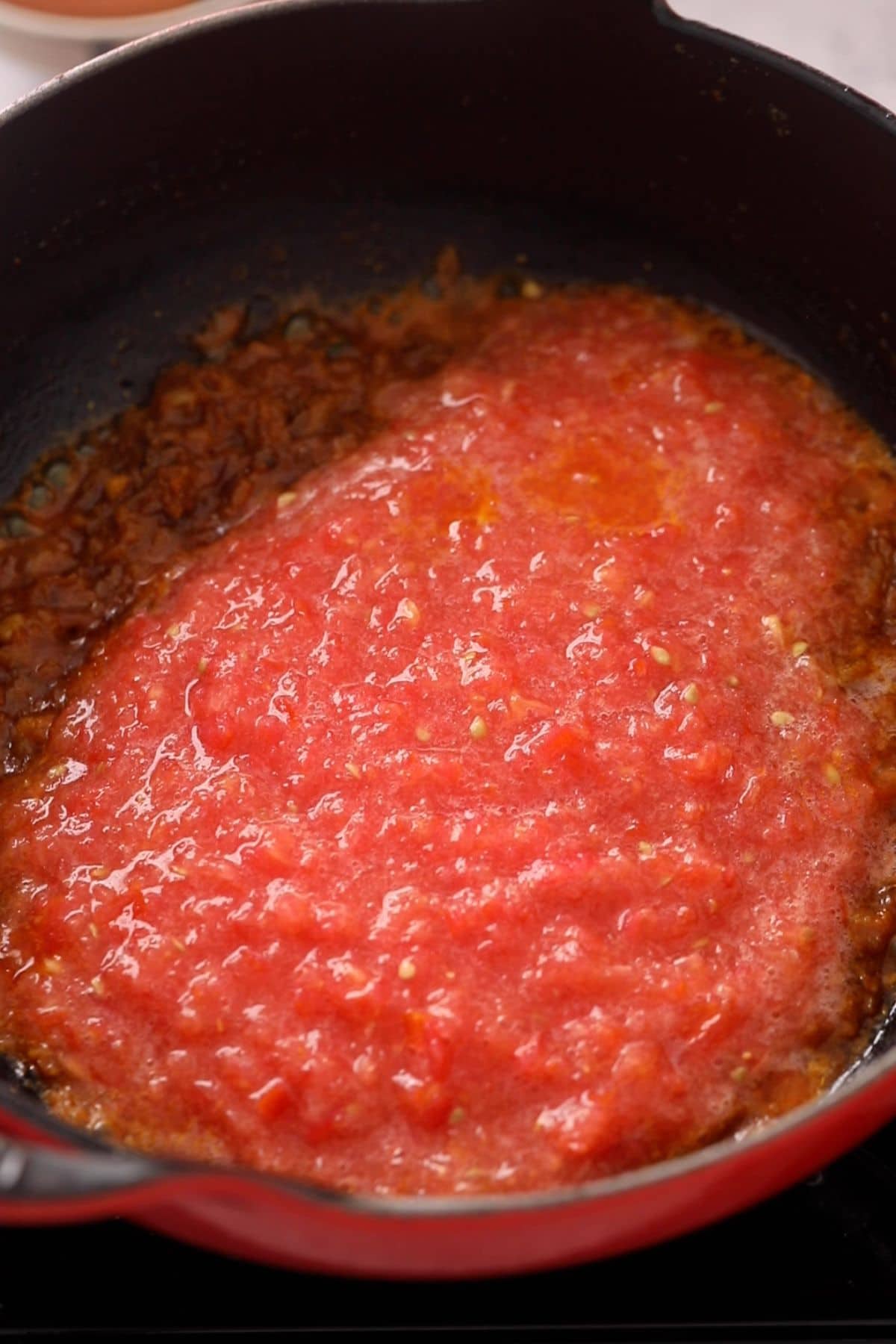 Crushed tomatoes are added to the masala.