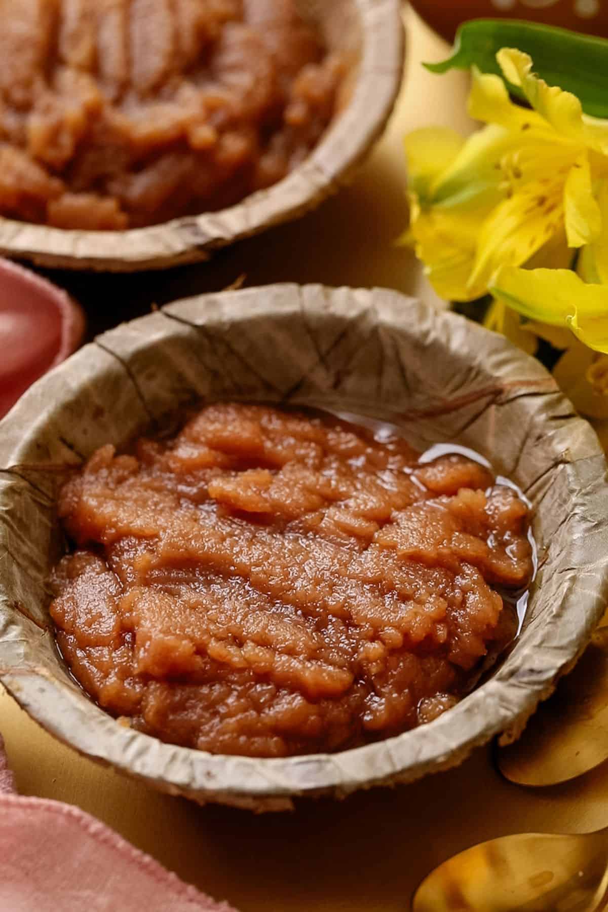 Side view of wheat flour halwa with yellow flowers in background.