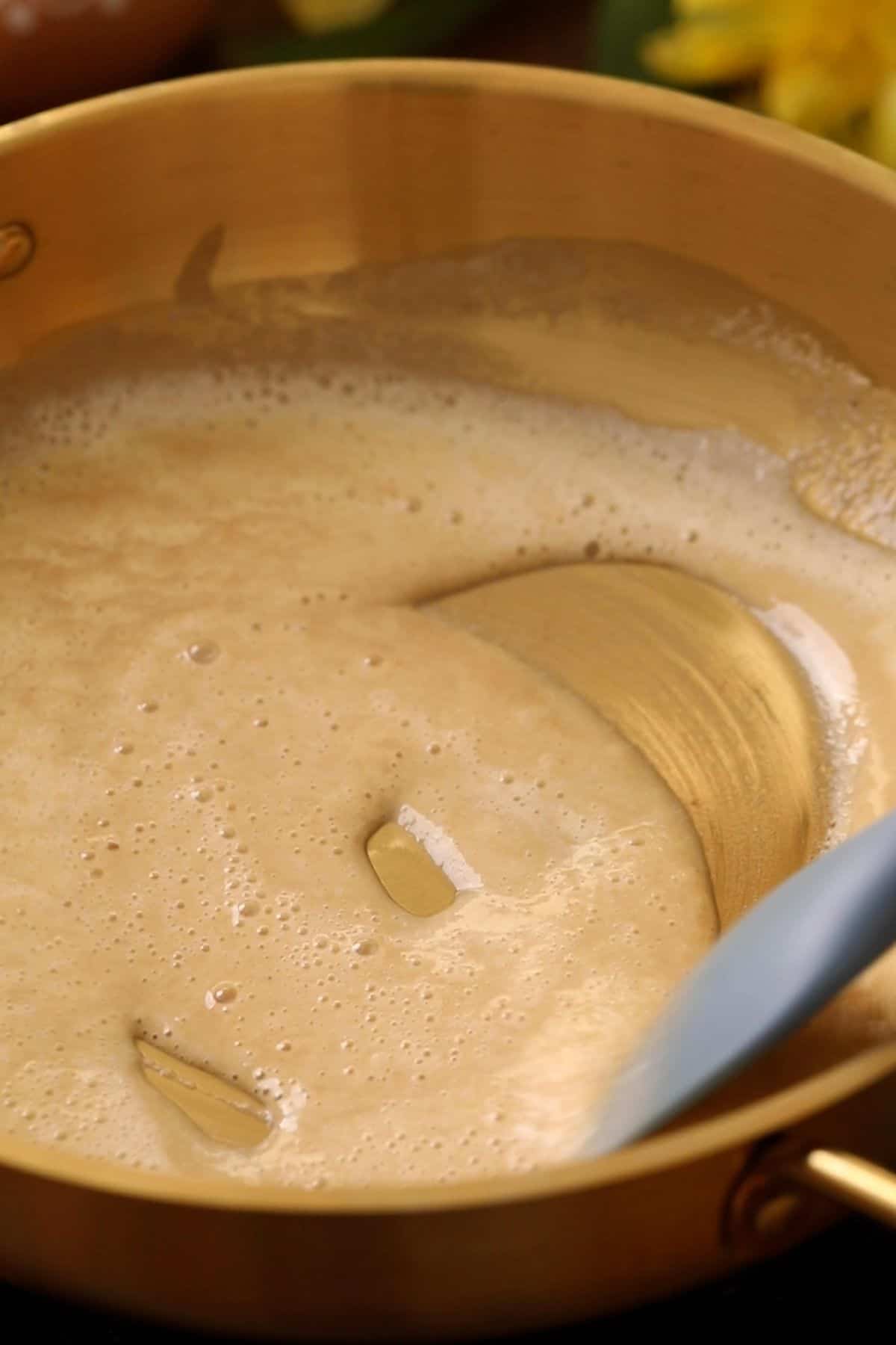 Ghee and flour mixture is being stirred slowly on low heat.