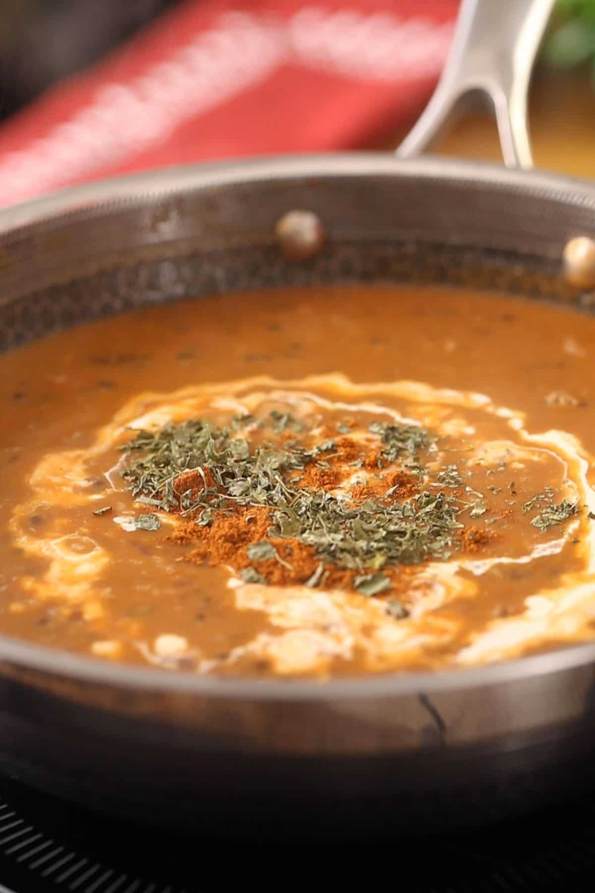 Finishing dal makhani with heavy cream, garam masala and kasuri methi.
