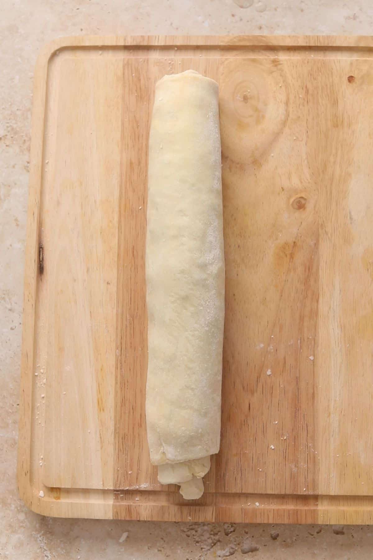 Samosa puff pastry roll all shaped and placed on a wooden board.