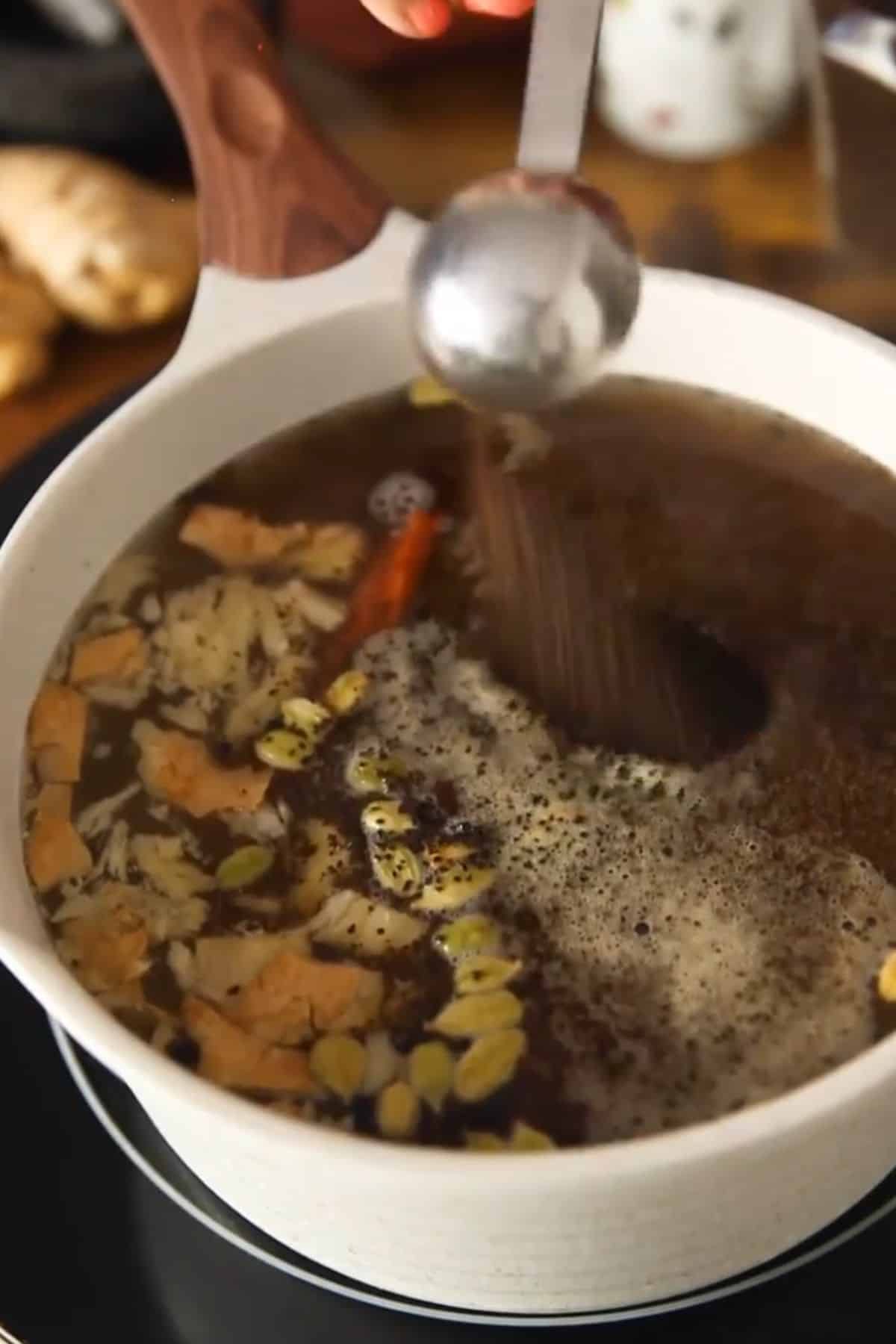 Loose black tea leaves are added to the pot of boiling water.