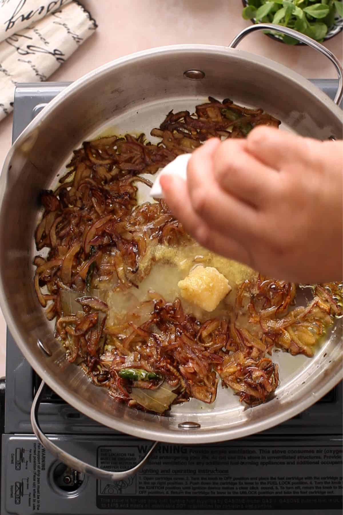 Ginger and garlic is added to browned onions along with some water.