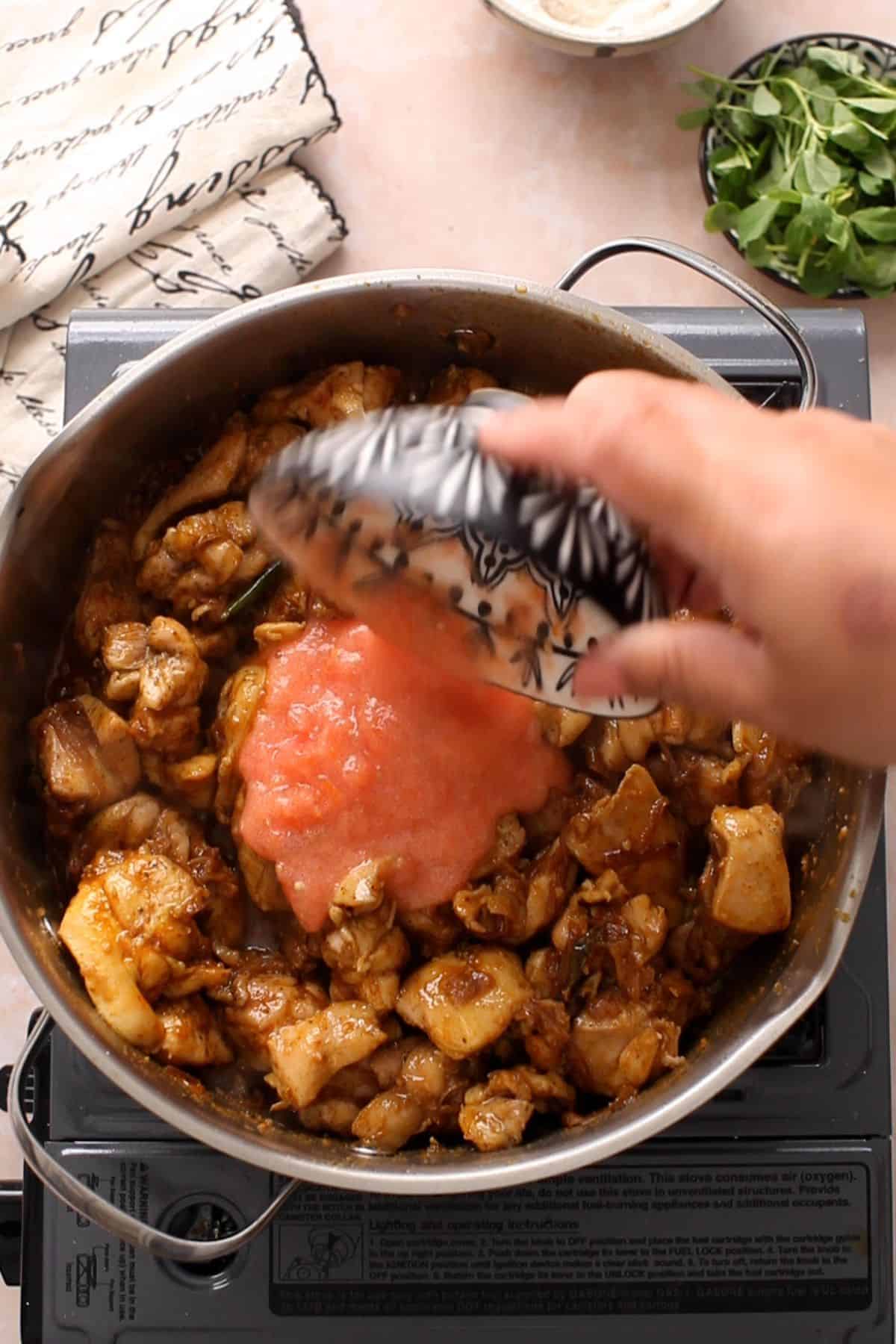 Crushed tomatoes are added to the chicken.