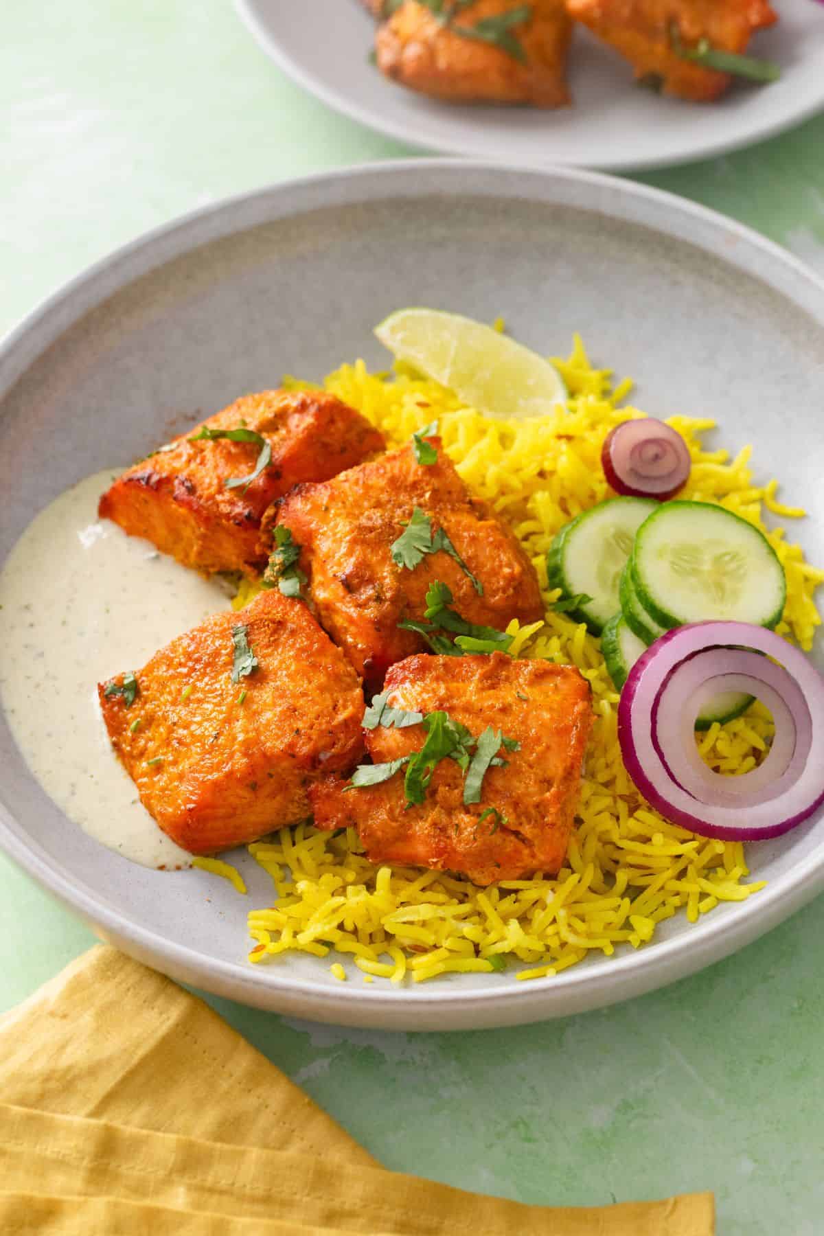 Tandoori Salmon Tikka served over yellow rice in a gray plate.