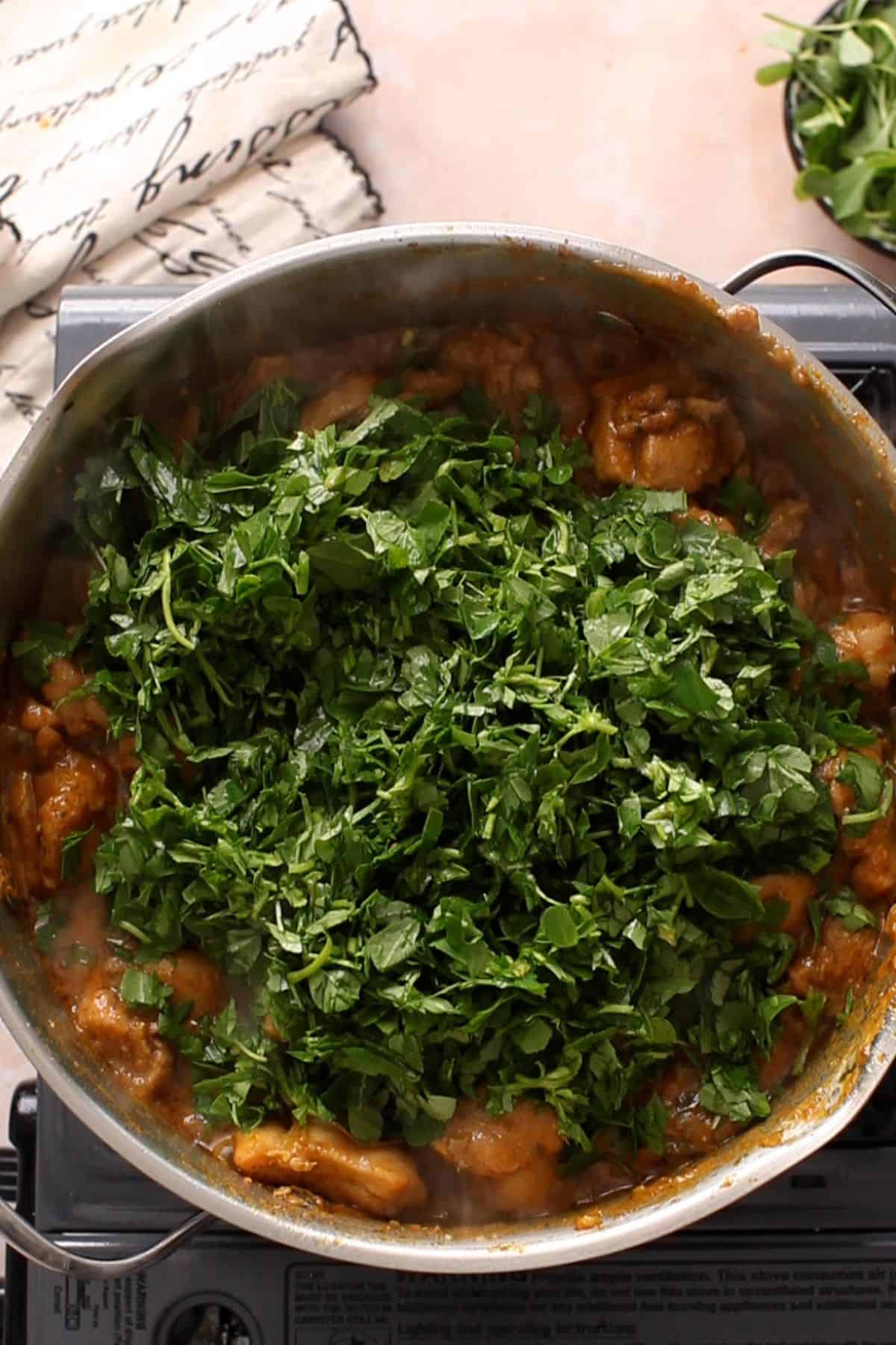 Fresh chopped mehi is added to the cooking pot.