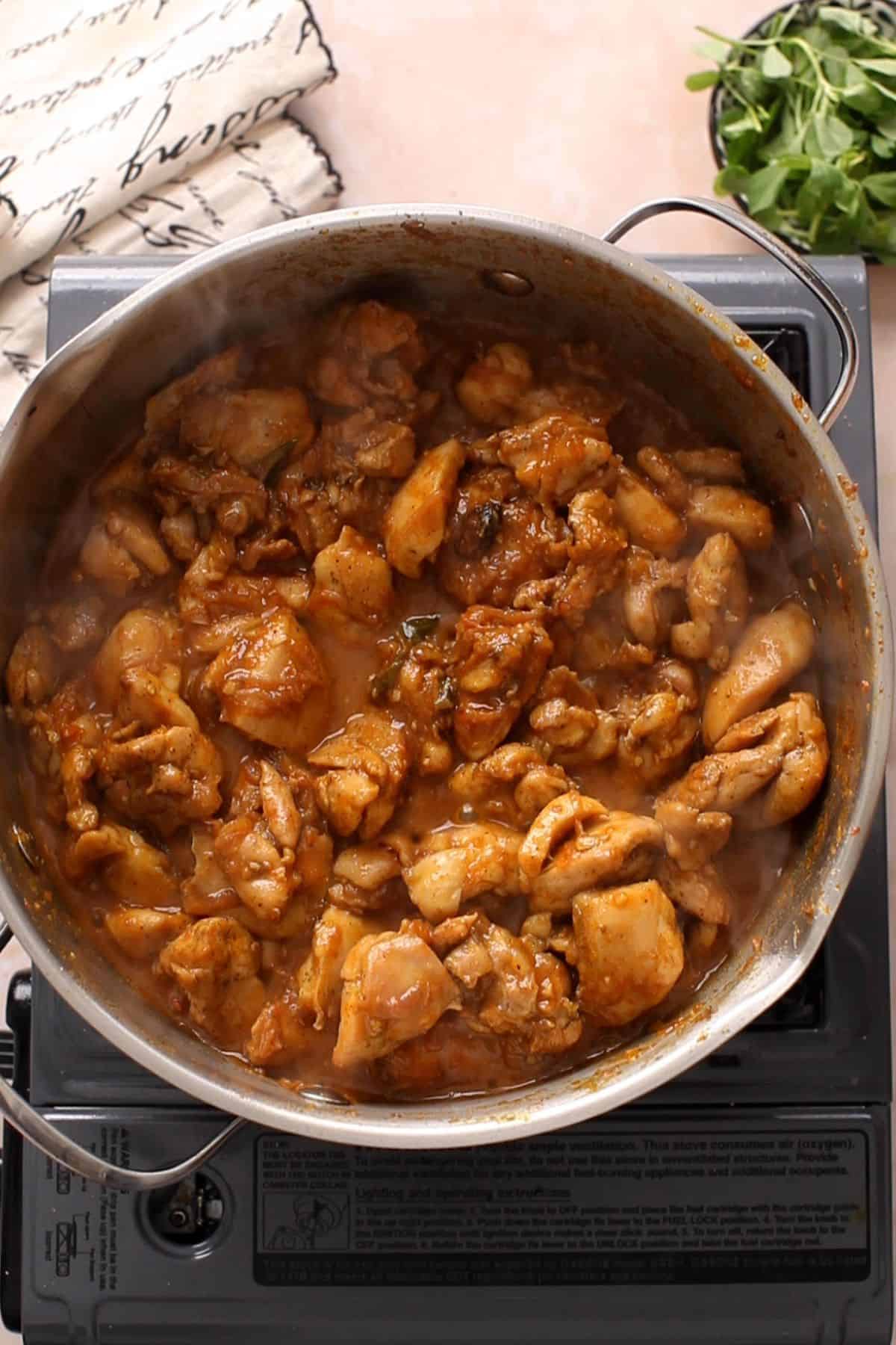 Chicken is cooked with tomatoes until oil begins to release.