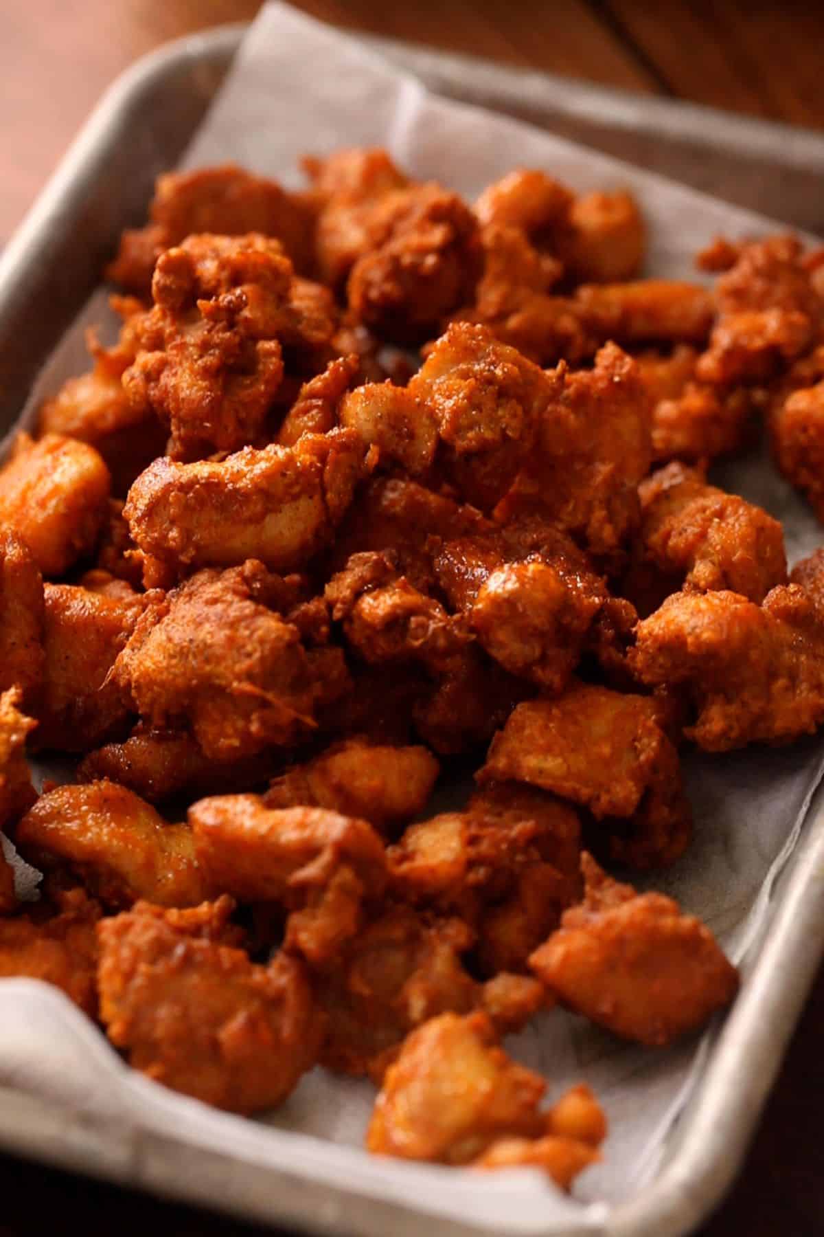 Deep fried crispy chicken is drained on paper towel.