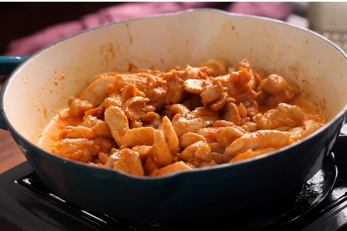 Chicken is partially cooked and then transferred to a plate.