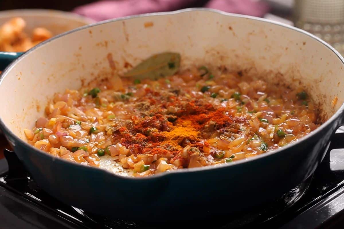 Powdered spices are added to browned onions.