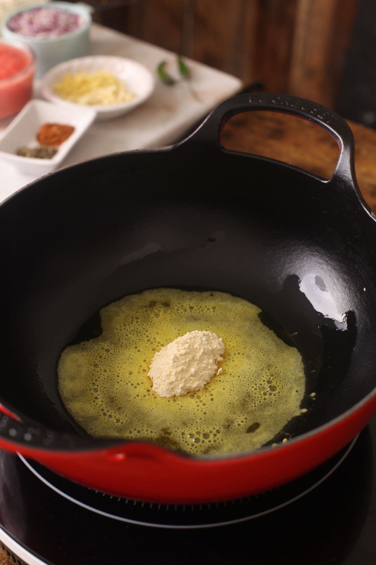 Gram flour is added to oil in a cast iron kadai.