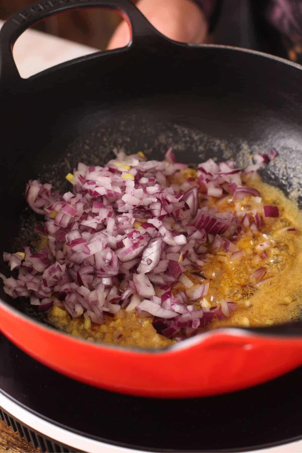 Chopped onions is added to the cast iron kadai.