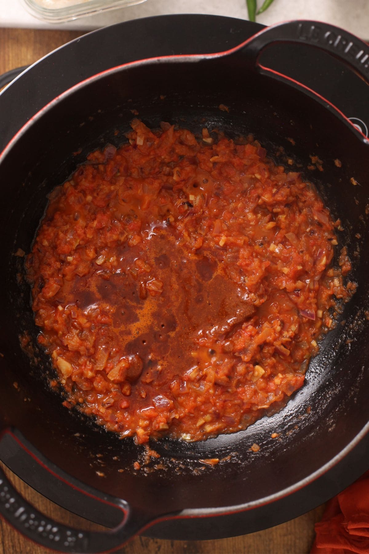 The roasted spices and besan mixtures is added back to the tomato masala in the iron kadai.