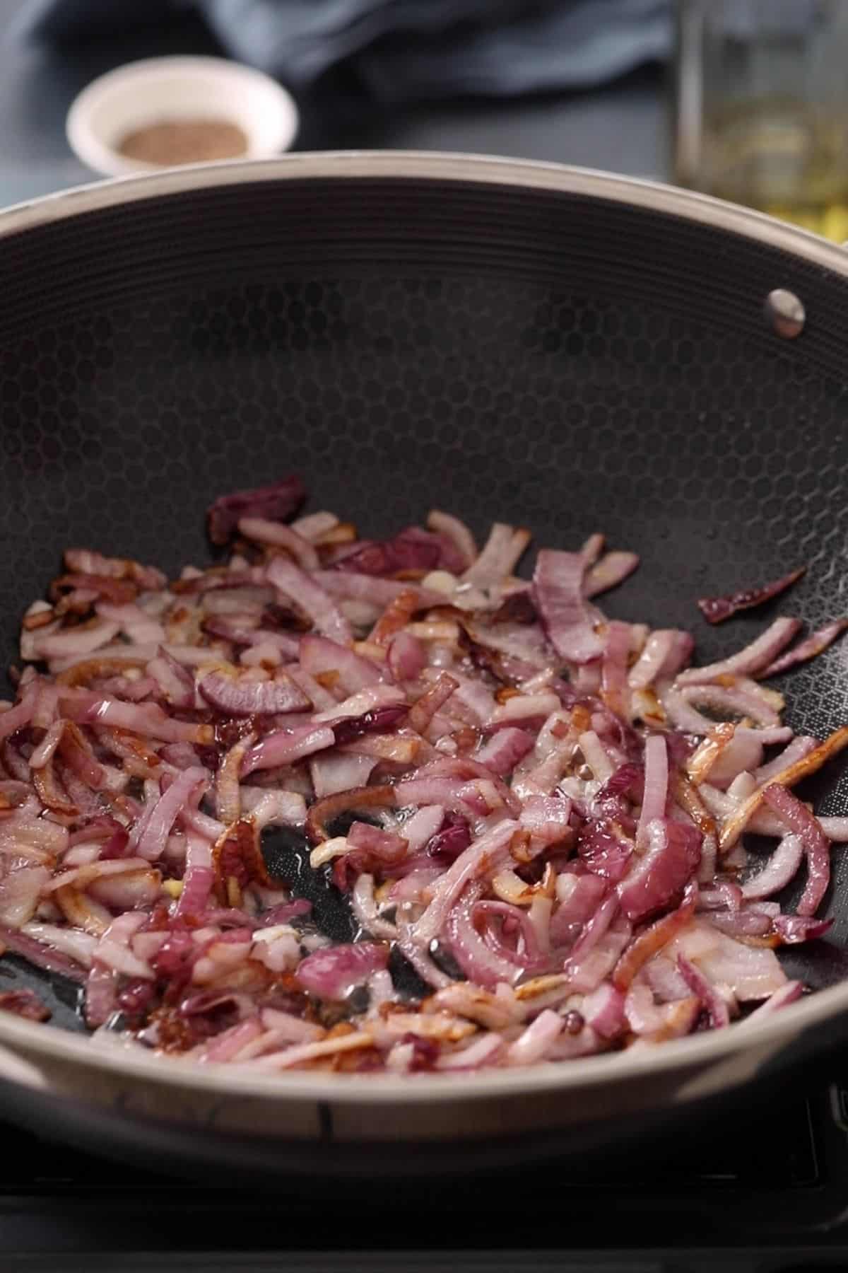 Browned onions in a large black wok.