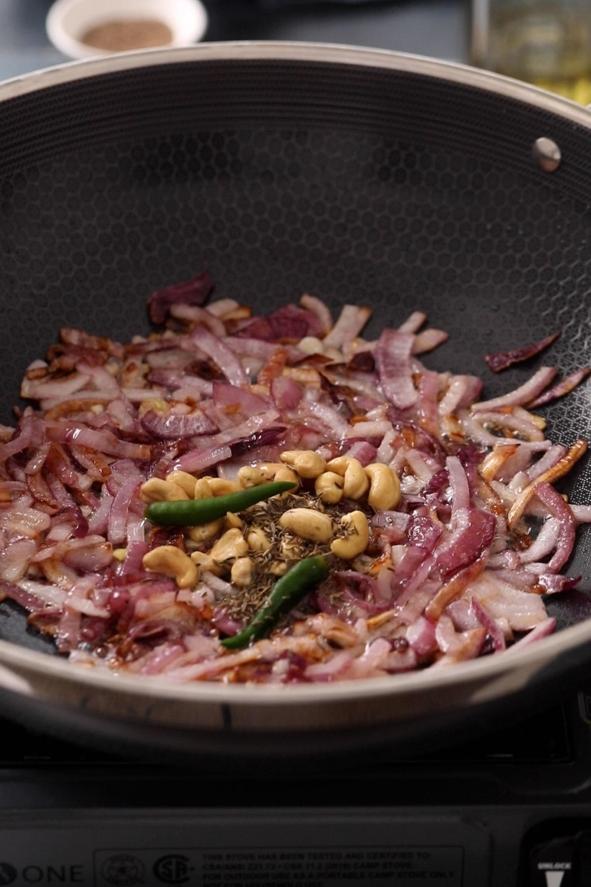 Cashew, cumin and green chillis are added to the browned onions.