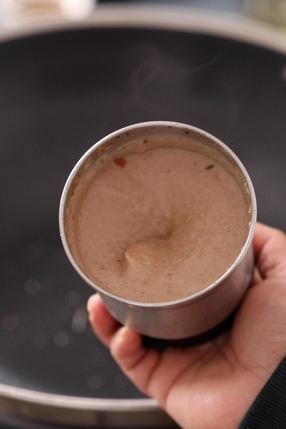 A small blender jar with onion and cashew paste.