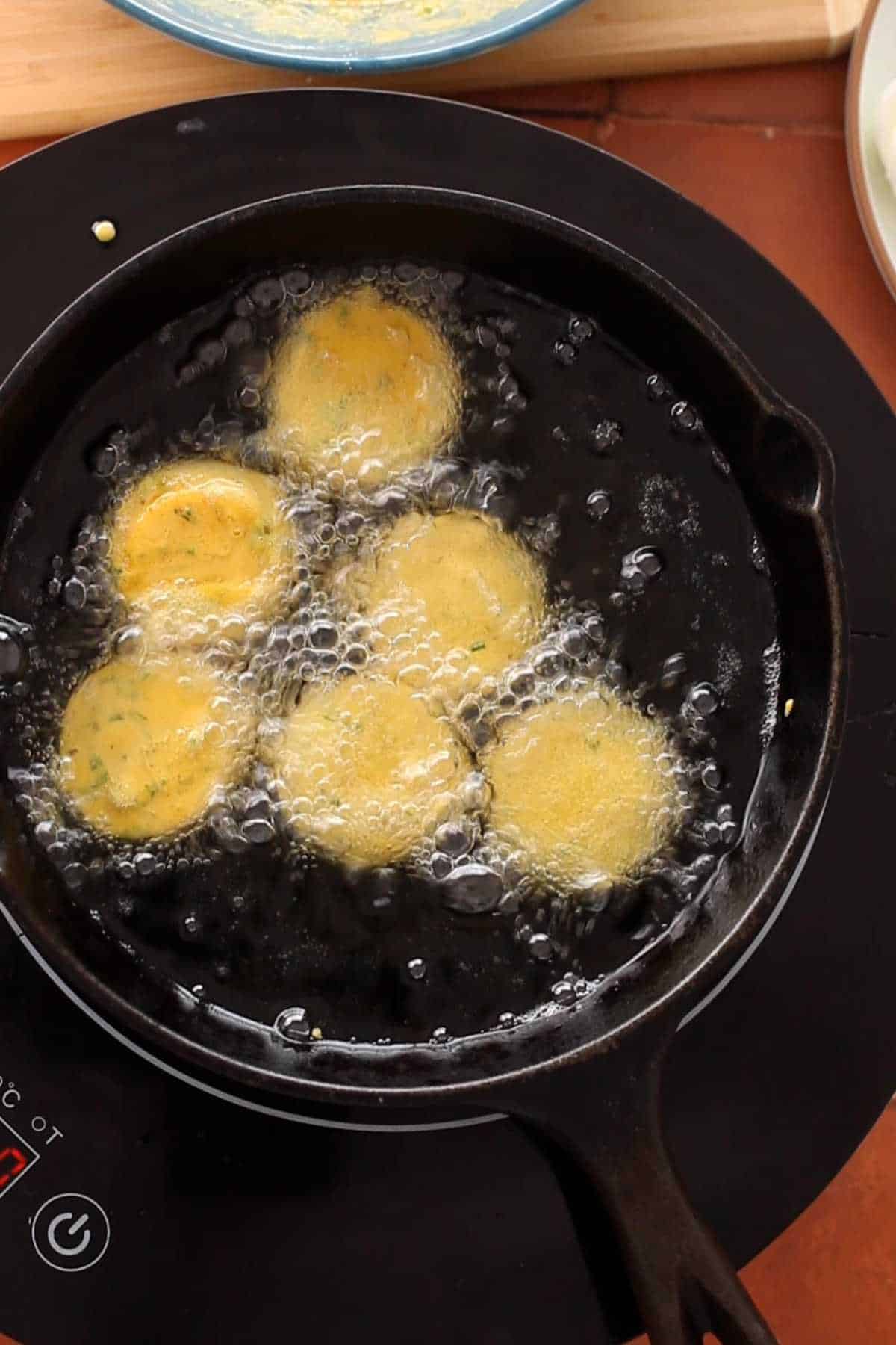 Egg fritters sizzling in hot oil.