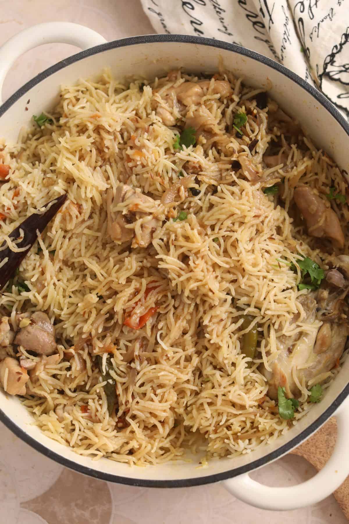 Cooked chicken pulao in a wide enamaled cast iron pot.