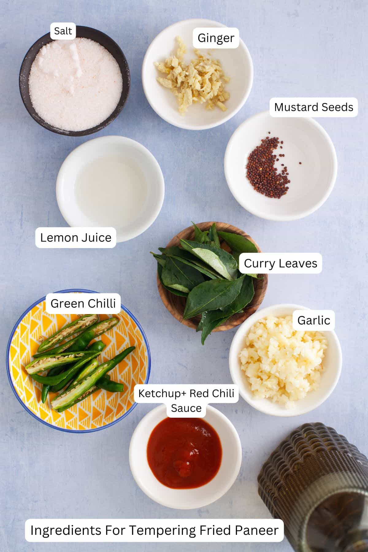 Ingredients needed to temper fried paneer placed on a light blue background.