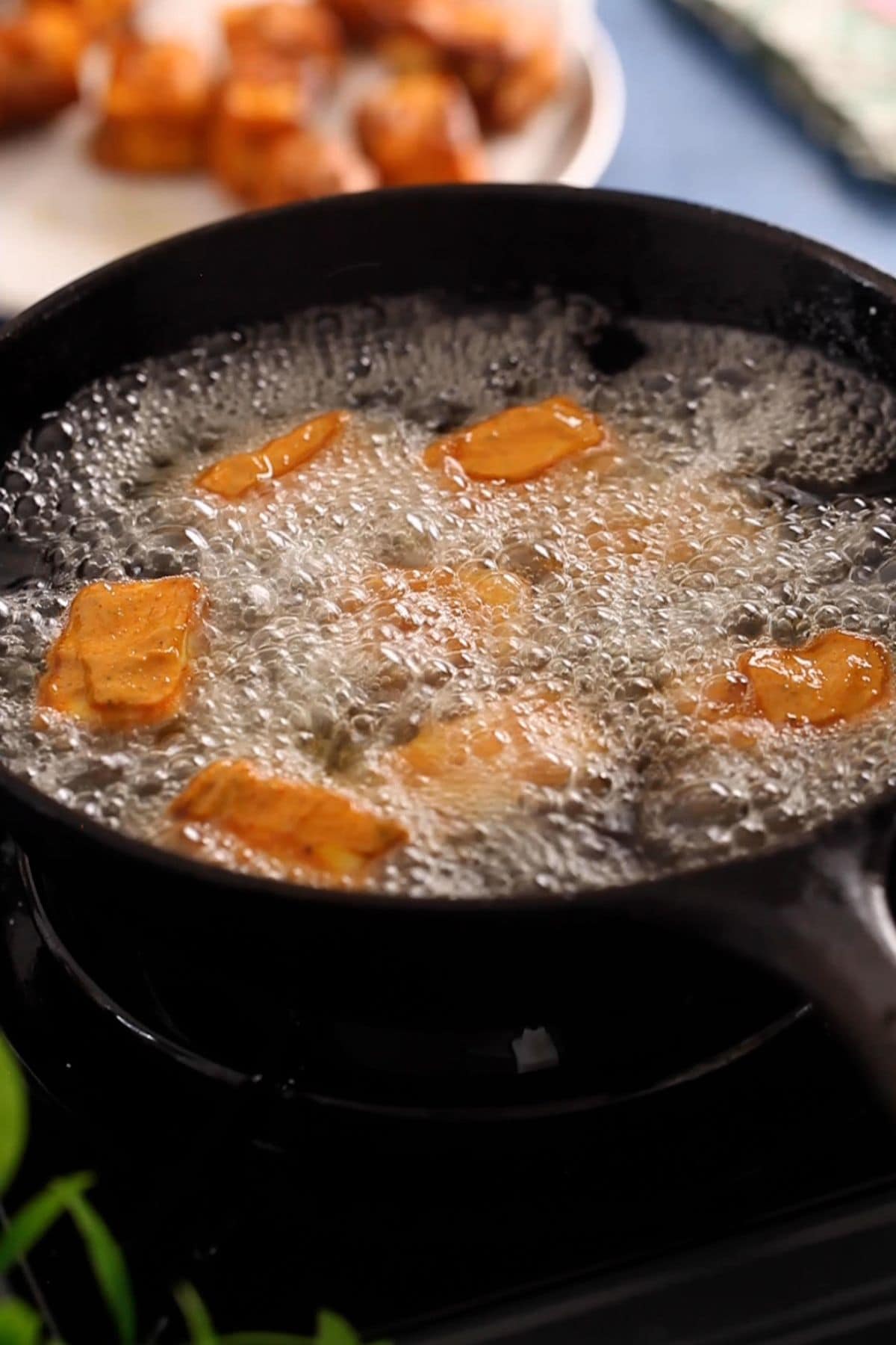 Paneer cubes are fried in an cast iron skillet.