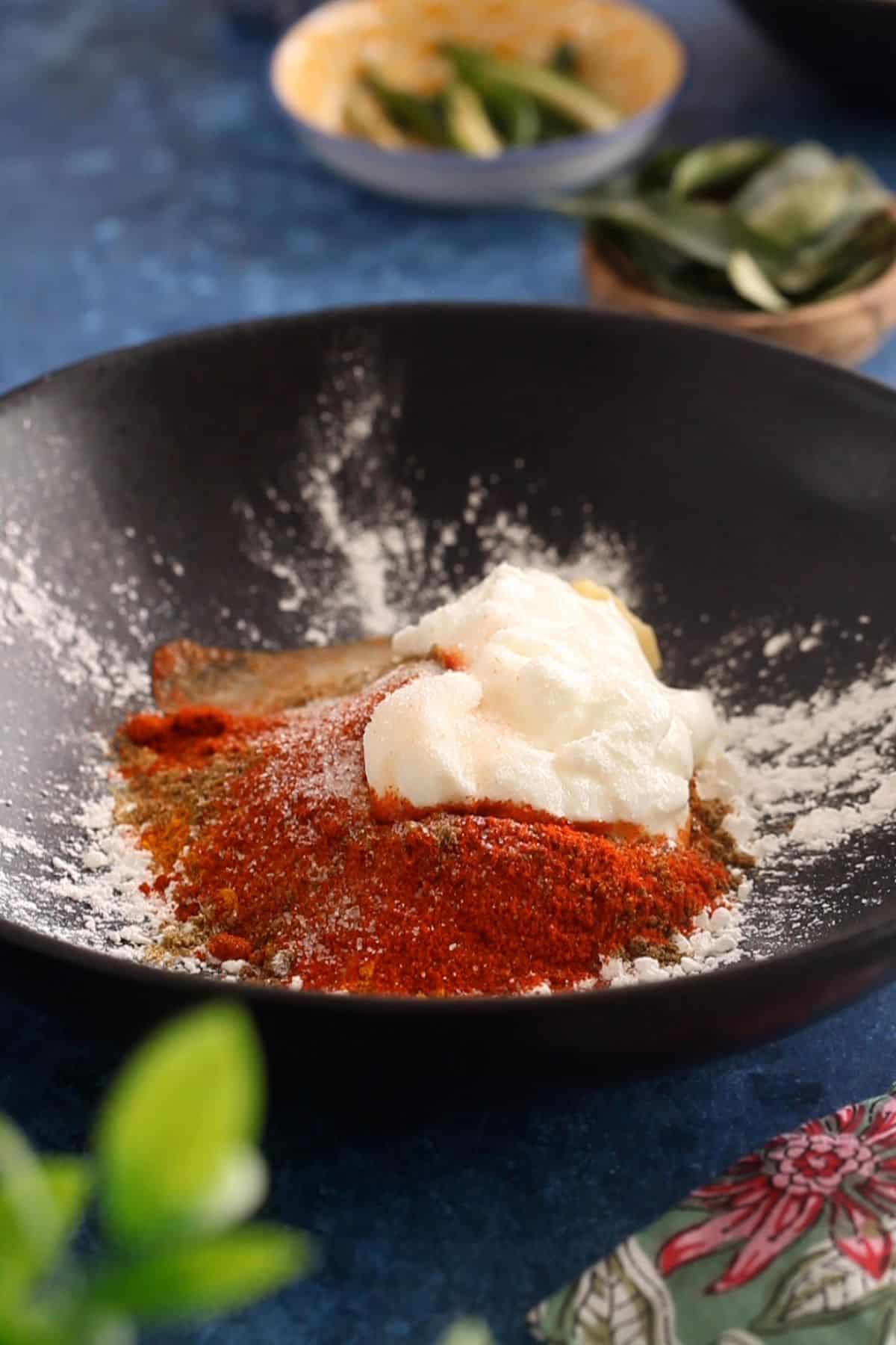 Cornstarch, rice flour, ground spices and yogurt are added to a mixing bowl.