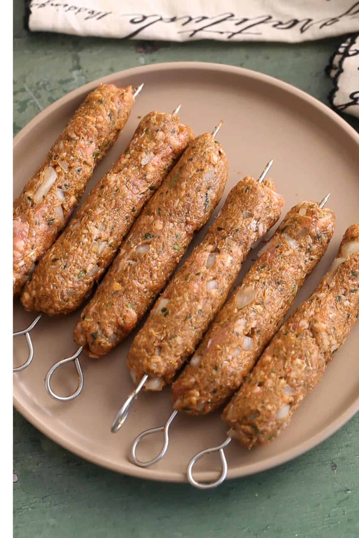 Shaped seekh kebabs placed on a brown plate.