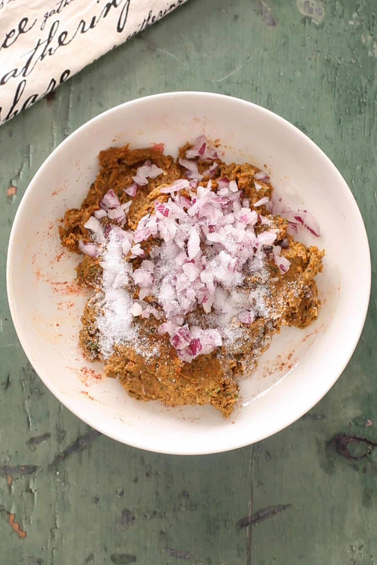 Onions and salt are added to seekh kebab mixture.