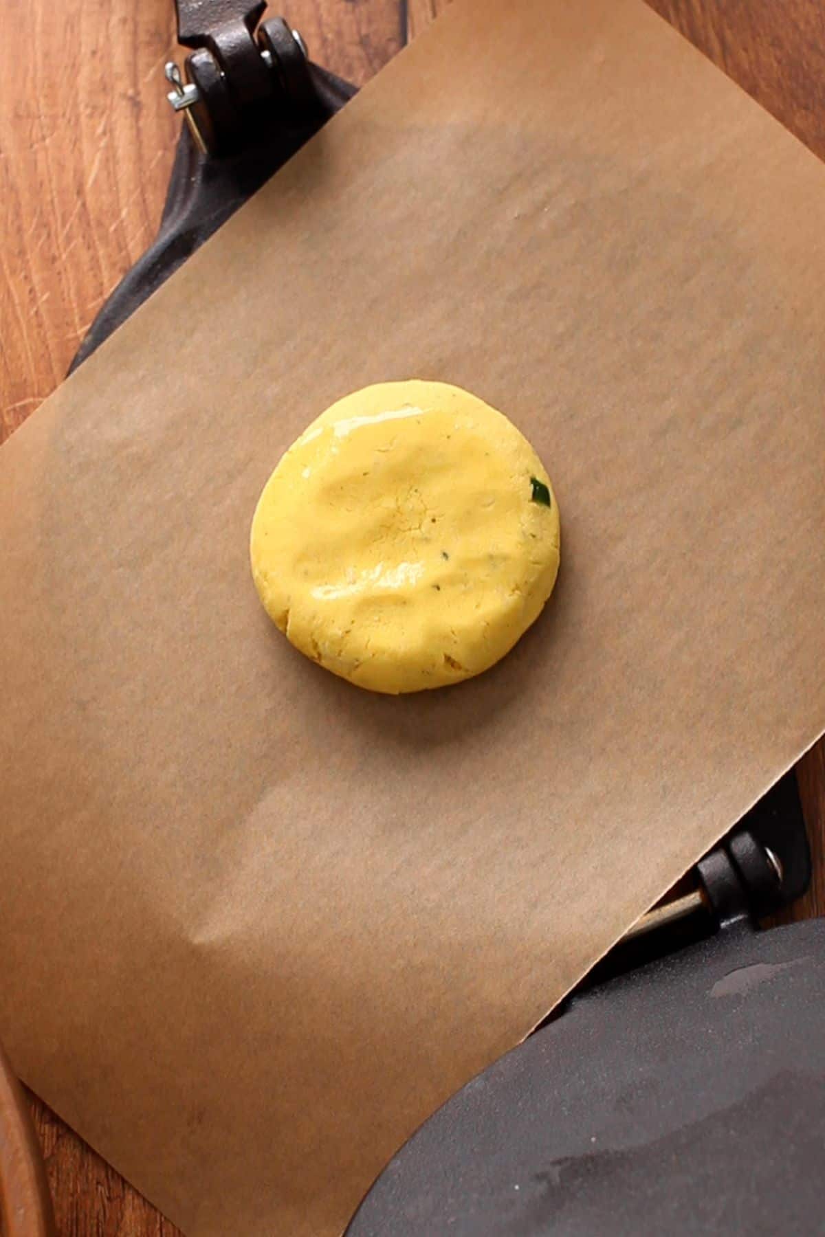 A ball of dough is placed on a brown parchemnt paper sheet.