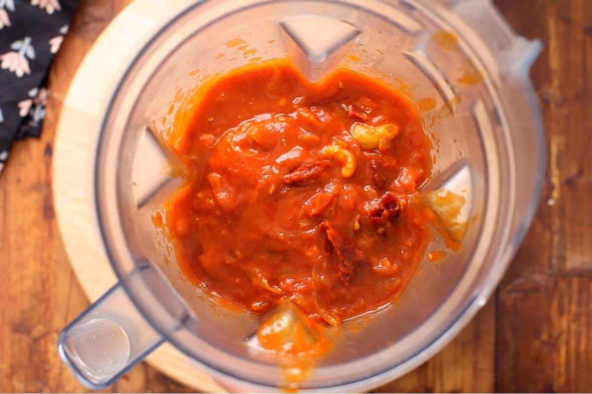 Onion tomato sauce is added to a blender jar.