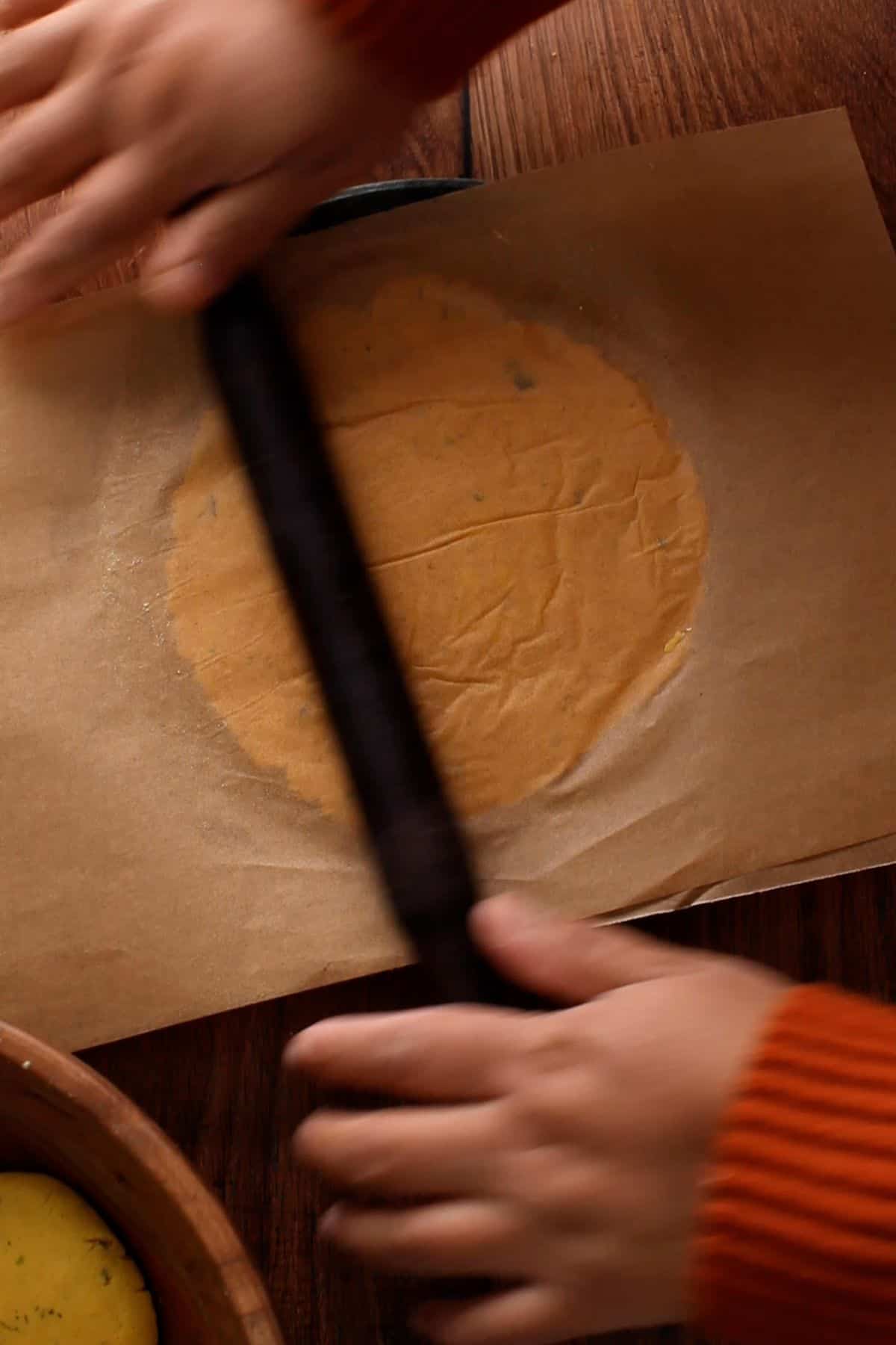 Rolling makki roti with a rolling pin.