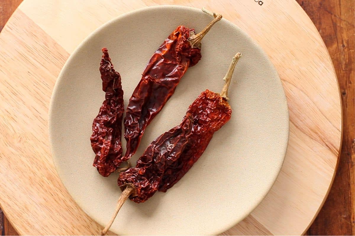 Whole Kashmiri Chilies placed on a mustard plate.