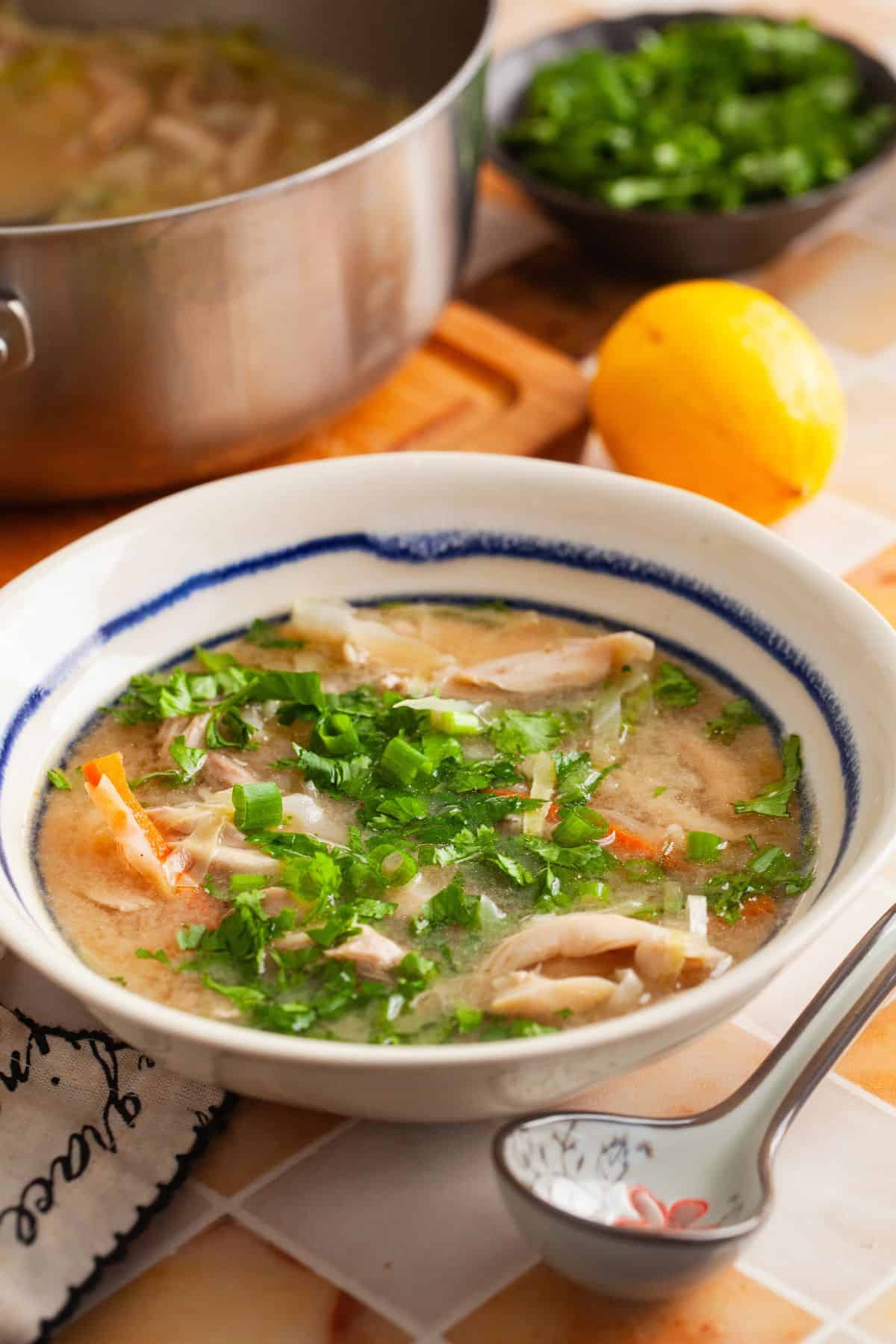 Piping hot bowl of chicken soup topped wuth chopped cilantro and scallions.