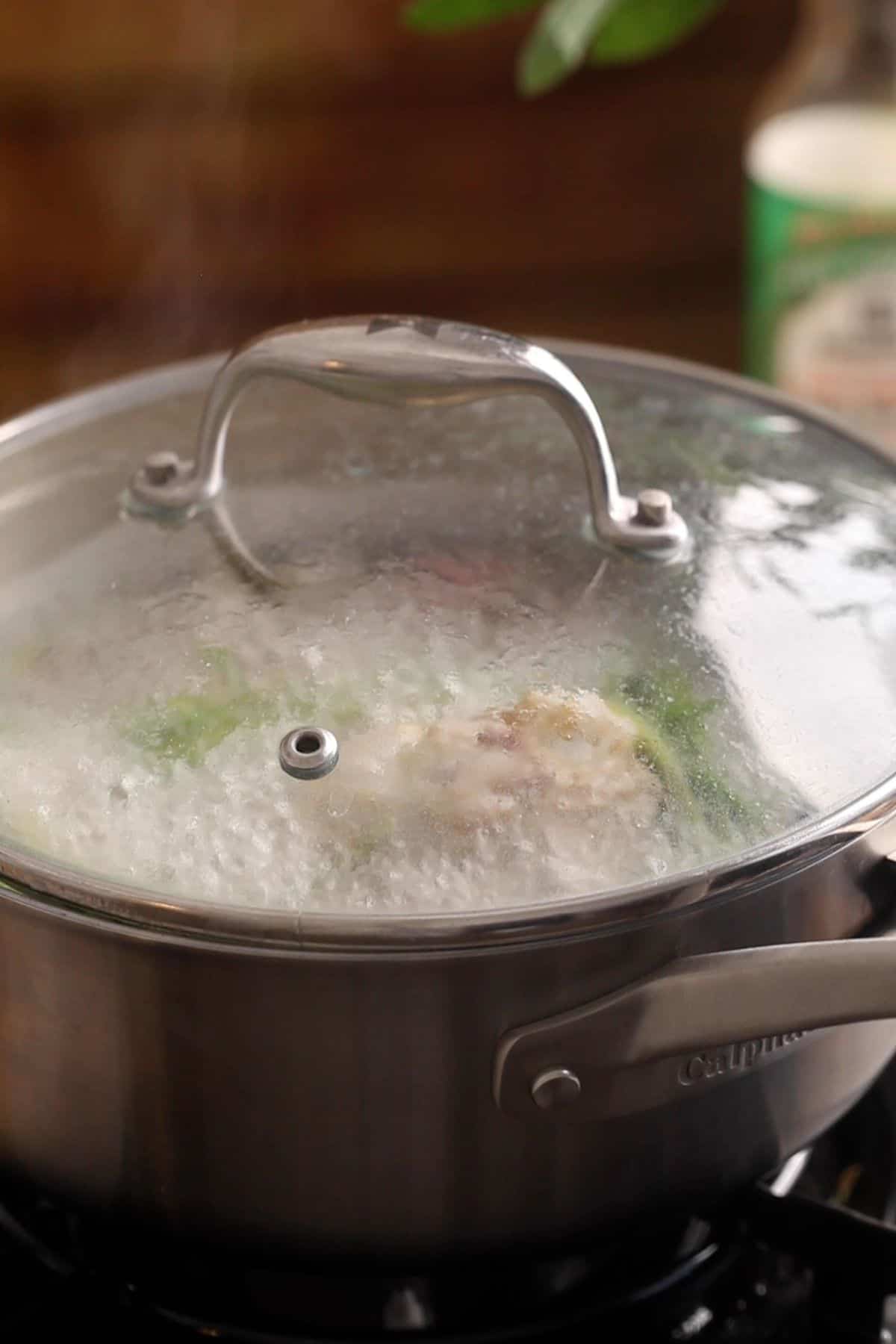 Chicken broth is slow cooking on stove.